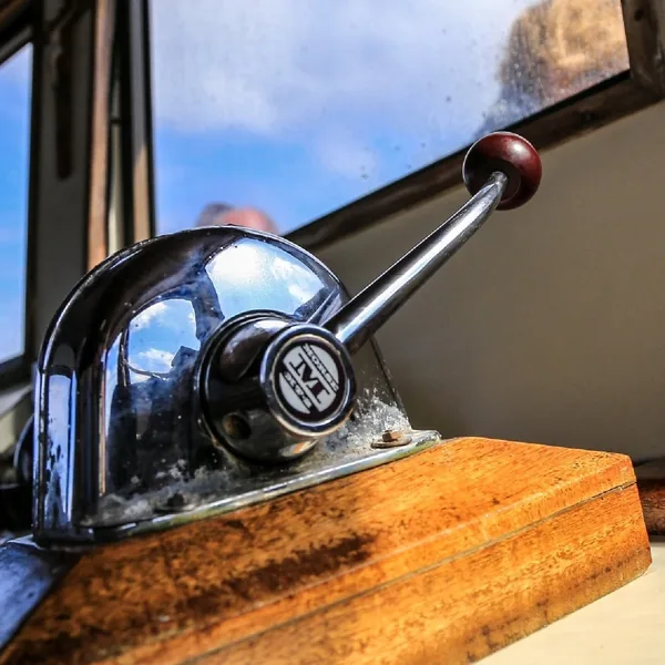 Original throttle lever on its wooden console, light through the wheelhouse window